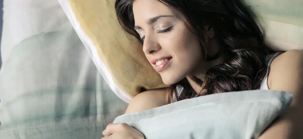 Une jeune femme endormie, la joue enfoncée dans un oreiller