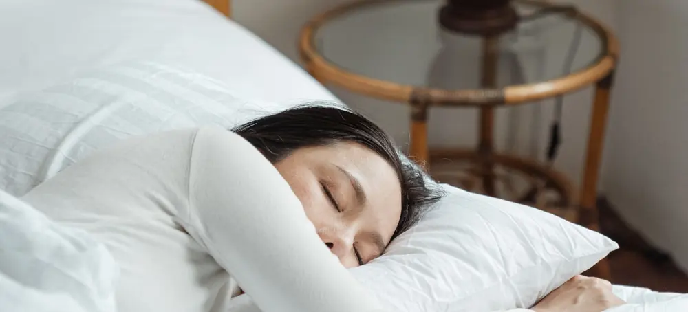 Une femme endormie sur le côté, une lampe sur la table de chevet