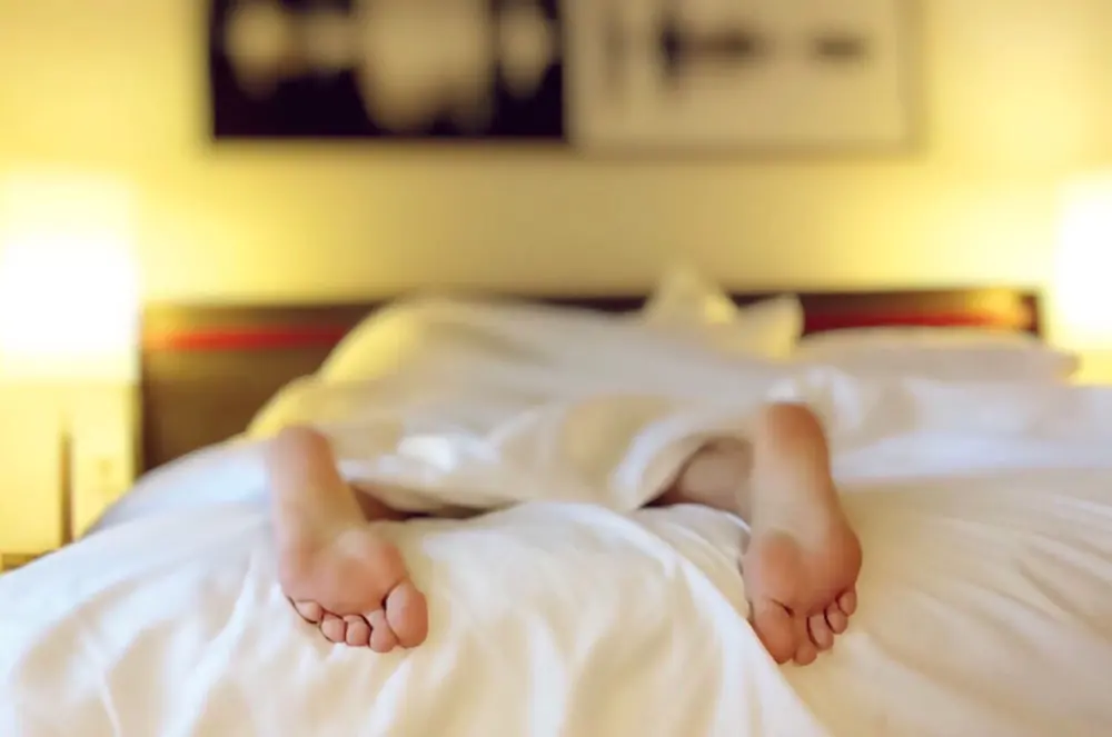 Les pieds d’une personne allongée sur un lit blanc